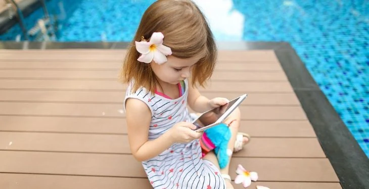 Young girl looking at cellphone next to the pool